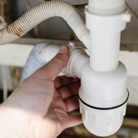 Klempner demontiert einen Siphon in der Küche (Nahaufnahme)